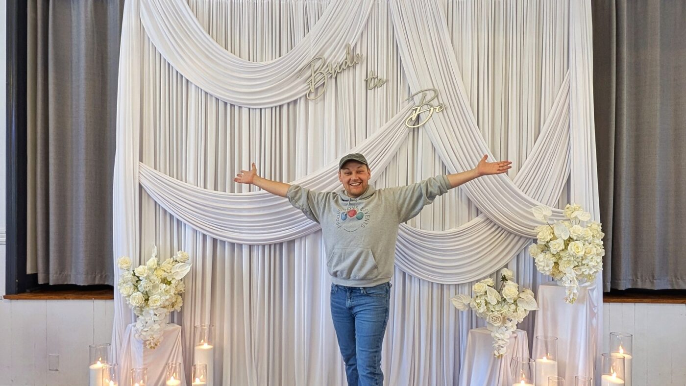 Pawel standing in front of a drapery backdrop with candles and florals.