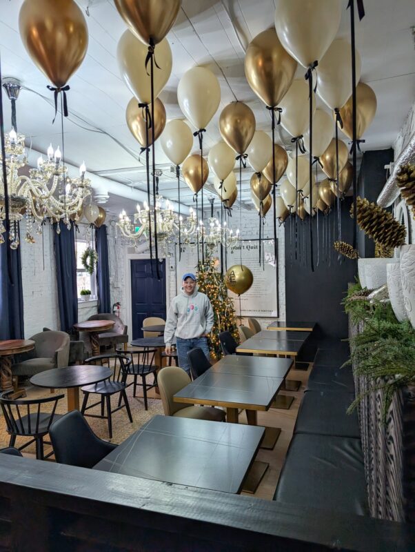 Pawel Rzeznik installing metallic helium balloons above an elegant dining space.