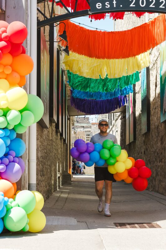 Pawel Rzeznik beneath a rainbow balloon entrance created for a Pride festival.