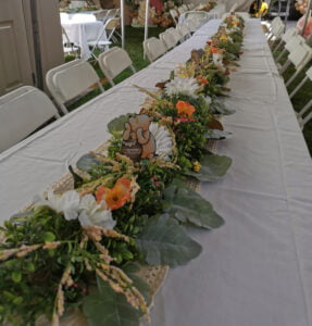 Table with a Winnie the Pooh themed runner adorned with mixed floral arrangements and Pooh cutouts.