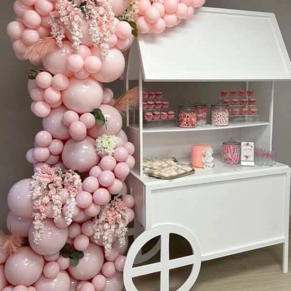 Dessert cart adorned with pink balloons and flowers, showcasing an array of sweets.