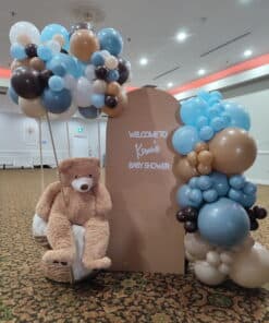 Teddy bear themed welcome sign with a giant teddy bear in a hot air balloon made of brown and blue toned balloons.