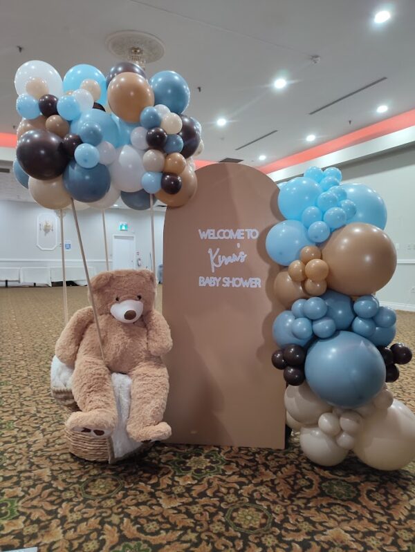 Teddy bear themed welcome sign with a giant teddy bear in a hot air balloon made of brown and blue toned balloons.