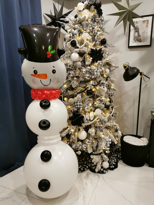 Balloon arrangement forming a snowman in front of a christmas tree.