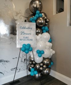 Welcome sign with a silver, white, and teal balloon column.