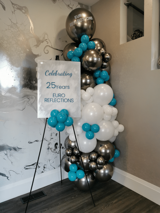 Welcome sign with a silver, white, and teal balloon column.