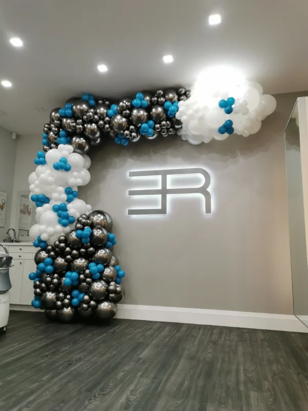 Black, white, and teal balloon garland climbing the wall and ceiling.