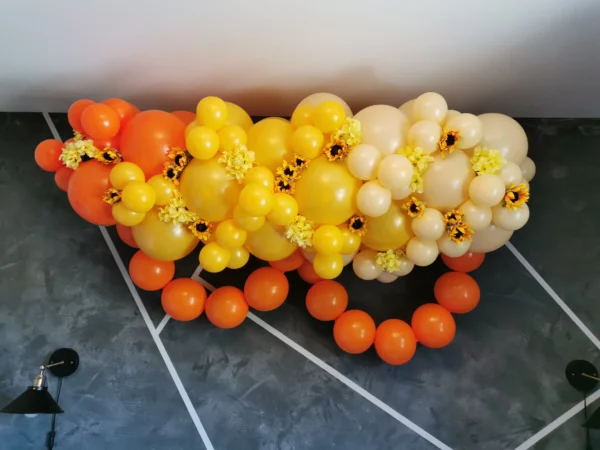 Orange and yellow balloon garland with sunflower accents.