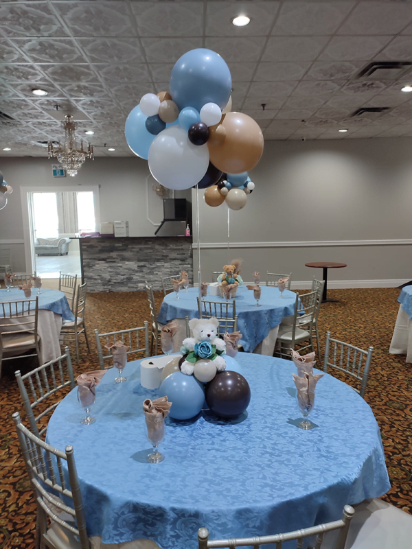 A bear themed centrepiece with a cluster of balloons suspended overtop to create a cloud.