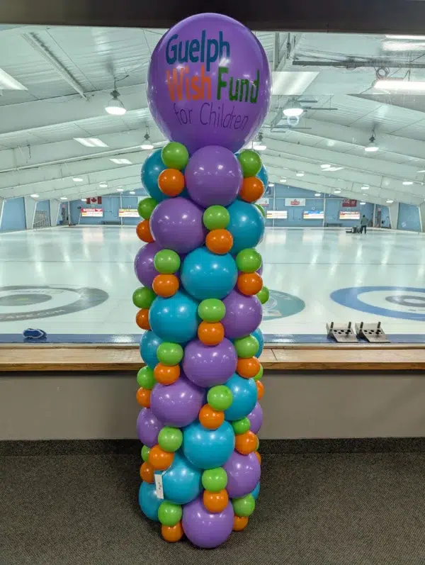 Colorful balloon column for the Guelph Wish Fund for Children, featuring purple, blue, green, orange, and yellow balloons in a curling rink.