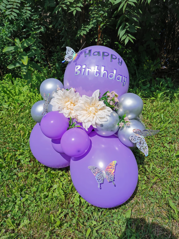 Purple balloon bouquet on grass.