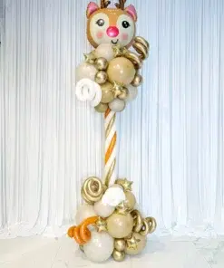 A tall balloon column topped with a reindeer-shaped balloon, featuring swirls of neutral and metallic balloons at the base.