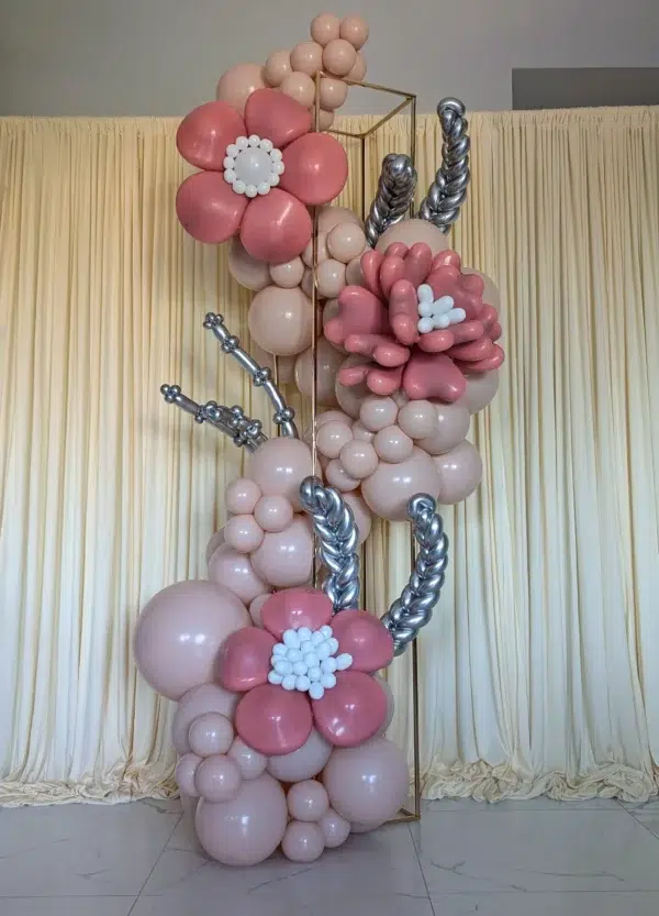 Colorful balloon floral arrangement featuring pink and white blooms, set against a soft beige backdrop. Ideal for events and celebrations.