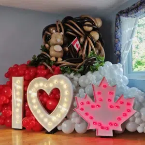 Colorful balloon display featuring "I ❤️ Canada" lights, a Canadian flag, and a balloon beaver in a festive setting.