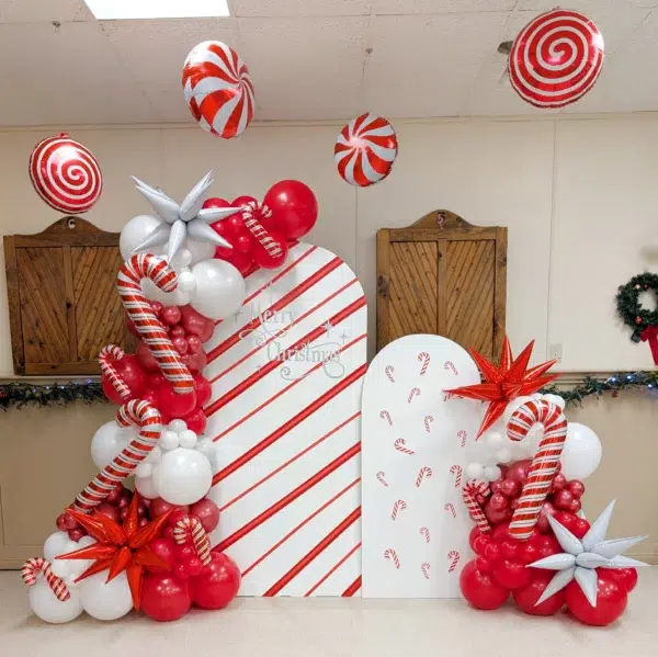 Christmas-themed backdrop featuring red and white balloons, candy canes, and festive decorations for holiday celebrations.