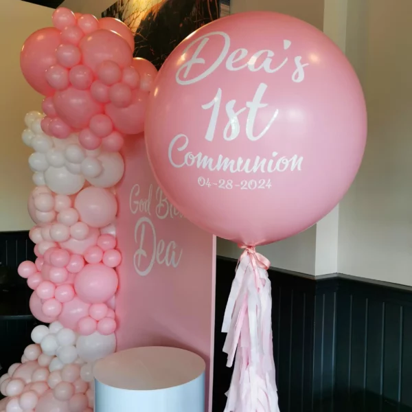 A large pink balloon with "Dea's 1st Communion" is displayed alongside a balloon arch for a celebration on 04-28-2024.