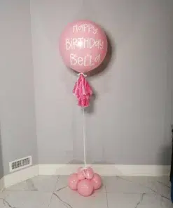 A large pink 24-inch helium balloon with a custom message, featuring a tassel tail and balloon base.