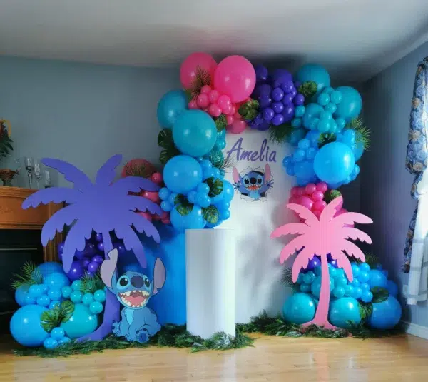 Colorful balloon arch decor featuring palm trees and a Stitch character cutout, ideal for a birthday celebration.