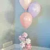 A pastel pink and lavender balloon bouquet with flower-shaped balloons at the base, perfect for celebrations.