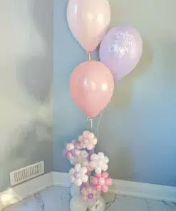 A pastel pink and lavender balloon bouquet with flower-shaped balloons at the base, perfect for celebrations.