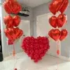 Two red heart-shaped balloon bouquets and a large red balloon heart sculpture displayed against a neutral backdrop