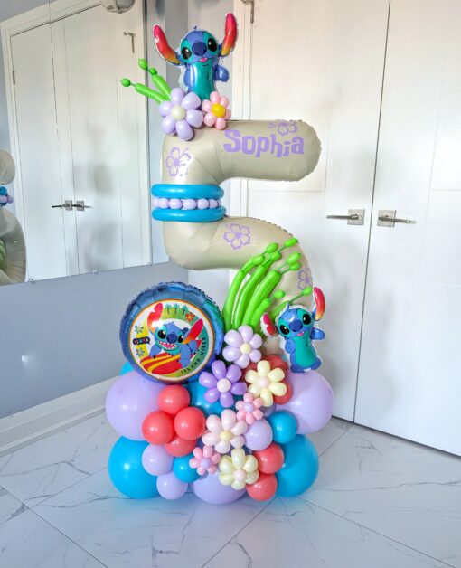 A vibrant balloon number stack featuring Stitch characters, tropical-themed floral balloon décor, customizable numbers, and personalized name decals.