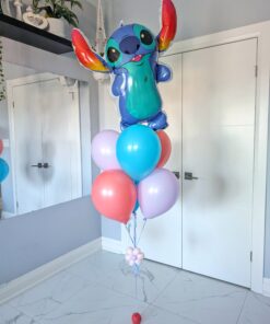 Stitch-themed balloon bouquet featuring a large colourful Stitch foil balloon and a cluster of pastel latex helium balloons with a small flower accent and a simple balloon weight.