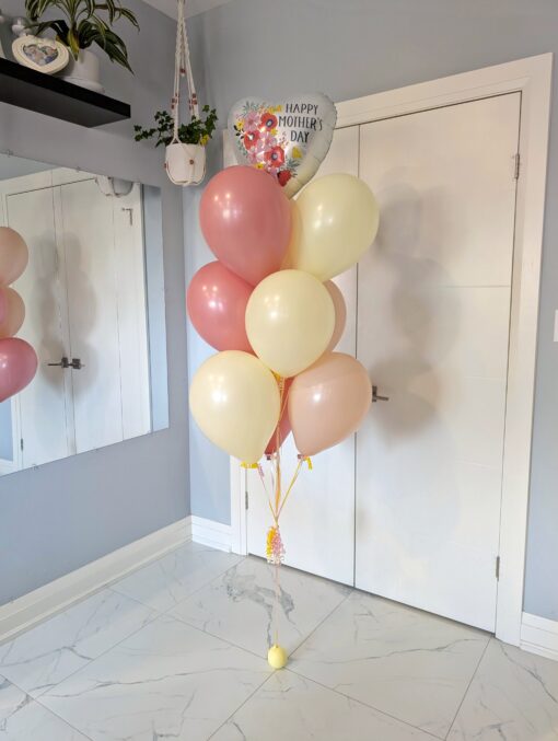 Elegant Mother’s Day bouquet with blush and cream latex balloons and a floral heart-shaped foil balloon, tied to a soft yellow water weight.