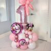 Minnie Mouse-themed balloon stack with a pink foil number balloon, polka dot balloon bow topper, and Minnie Mouse foil accents in pink, white, and metallic colours.
