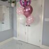 Helium balloon bouquet with a Minnie Mouse Orbz balloon, pink polka dot balloons, metallic rose balloon, and white balloon on a pink weight