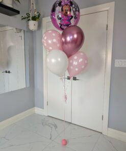 Helium balloon bouquet with a Minnie Mouse Orbz balloon, pink polka dot balloons, metallic rose balloon, and white balloon on a pink weight