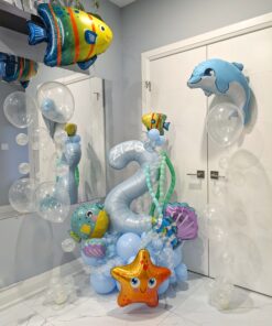 Under the Sea Splash Stack balloon number display with blue balloons, bubble accents, fish, dolphin, and starfish foil balloons for a birthday party.