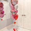 Romantic Valentine’s Day helium balloon bouquet featuring red, pink, and white heart-shaped foil balloons with a “Happy Valentine’s Day” balloon and a small balloon base.