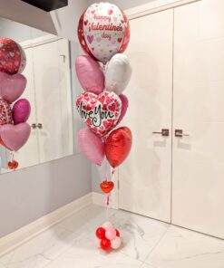 Romantic Valentine’s Day helium balloon bouquet featuring red, pink, and white heart-shaped foil balloons with a “Happy Valentine’s Day” balloon and a small balloon base.