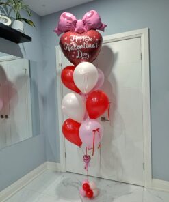 Valentine’s Day helium balloon bouquet with a large heart balloon, oversized pink bow, and red, white, and blush balloons on a weighted base