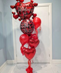 Tall Valentine’s Day helium balloon bouquet with oversized red foil heart balloons, Valentine print balloons, cascading ribbons, and a weighted base.