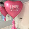 68-inch hot pink heart-shaped helium foil balloon with “I Love You This Much” text and tassel tail on a balloon base.