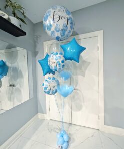 Blue “It’s a Boy” helium balloon bouquet with star foil balloons and clear bubble balloons on a light blue balloon weight base. 💙