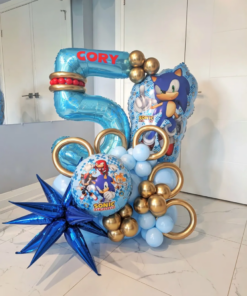 Sonic themed balloon number stack with blue balloons, gold ring accents, character balloons, and personalized name decal for a gamer birthday party. 🌀💙