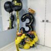 Construction themed balloon setup with black and yellow number stack, caution tape accents, helium bouquet, and personalized name decal