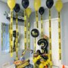 Construction themed balloon setup with number stack, ceiling helium balloons with caution tape tails, excavator balloon, pylons, and rock accents