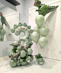 Dinosaur themed balloon setup with sage green number stack, helium bouquet, metallic dinosaur balloons, and personalized name decal