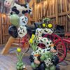 Farm themed balloon setup with cow print number stack, helium bouquet, greenery accents, and personalized name decal in barn setting