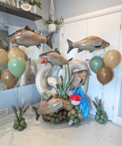 Fishing themed balloon setup with number stack, large fish balloons, cattails, and neutral green and tan colours for birthday display