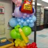 Colourful back-to-school balloon column with backpack balloon, oversized pencil and rainbow balloon clusters.
