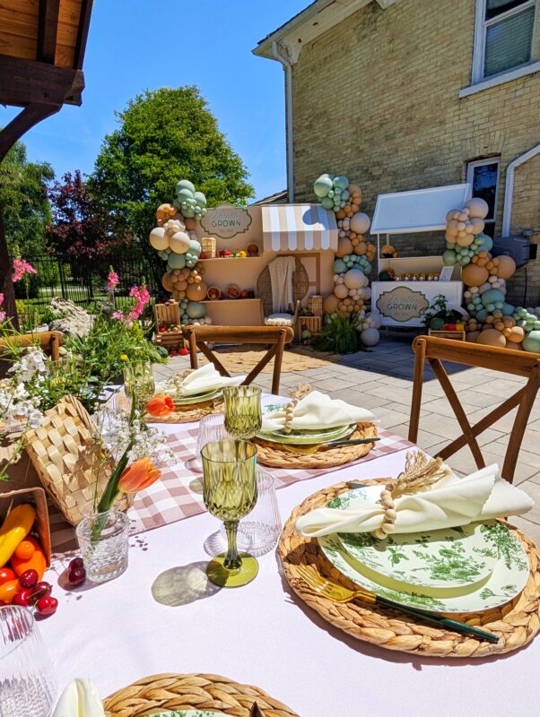 Locally Grown farmers’ market backdrop with striped canopy, balloons, produce and layered signage.
