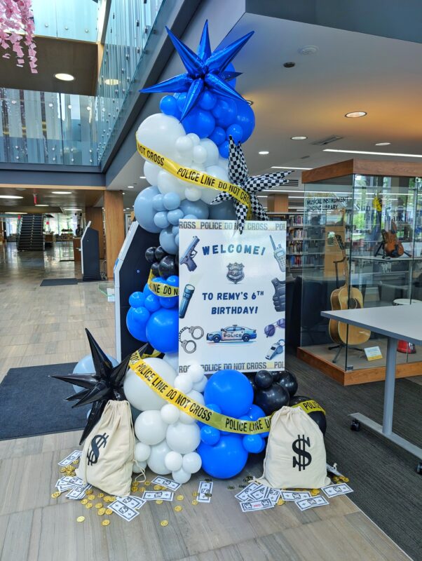 Custom welcome sign for Remy’s sixth birthday framed by police-themed balloons and caution tape.