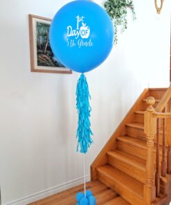 Blue personalized First Day of School jumbo helium balloon with a white grade decal, tassel tail and balloon base.