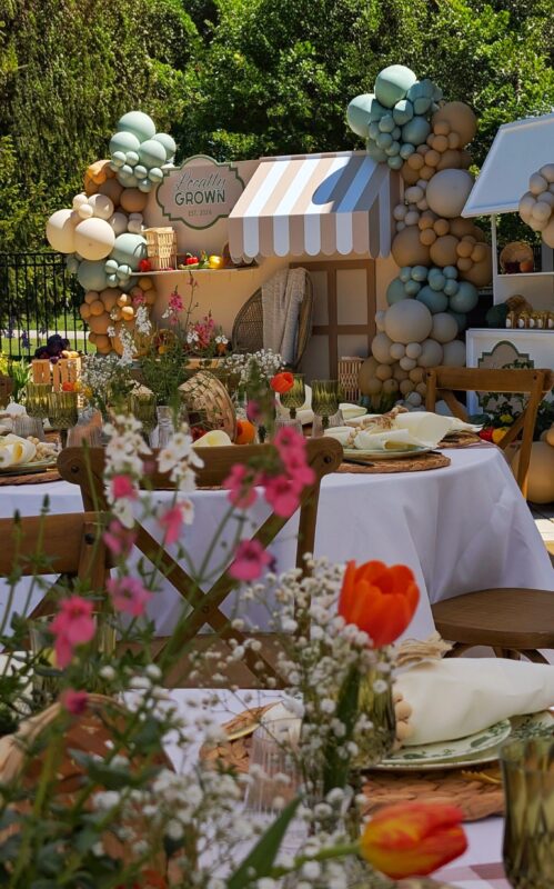 Fresh garden flowers, green glassware and layered place settings on a backyard baby shower table.