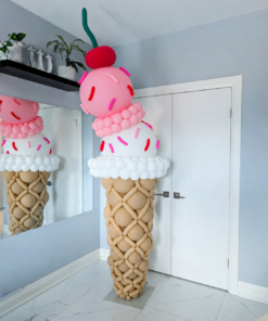 Giant balloon ice cream cone sculpture with two scoops, colourful sprinkles and a cherry topper.